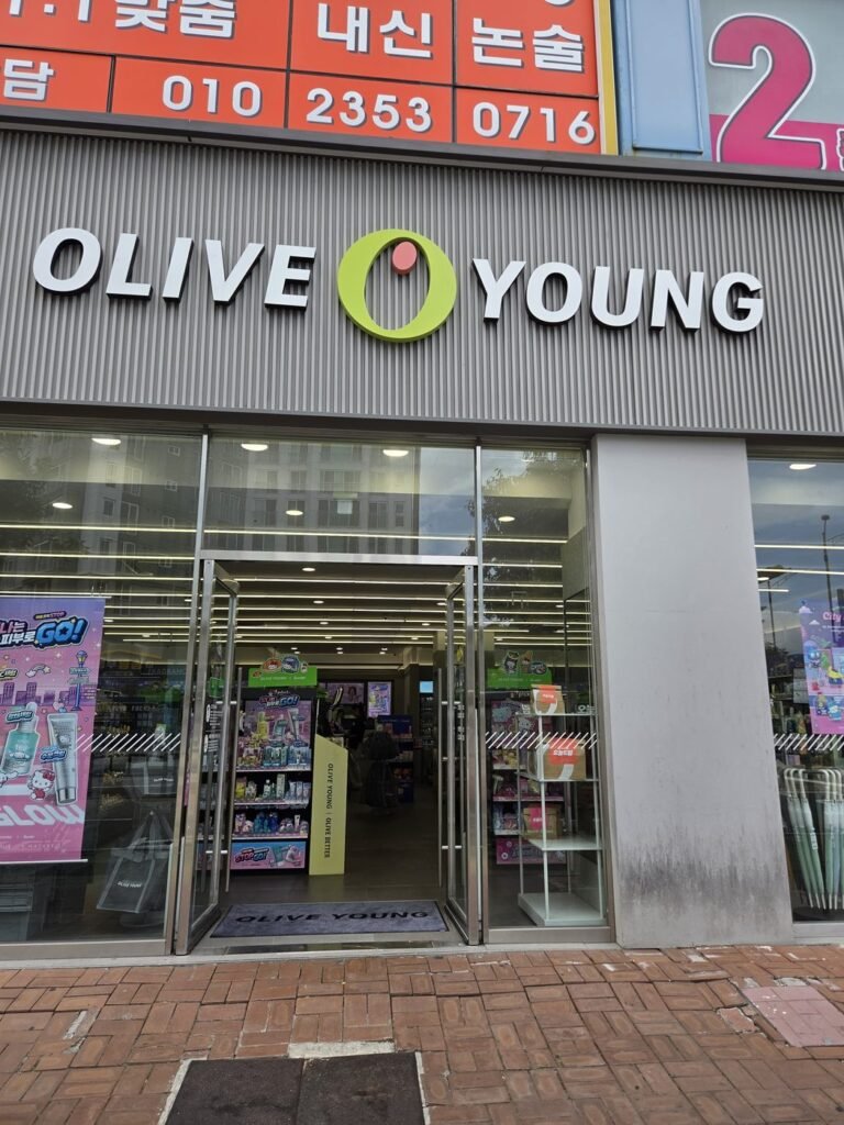 Olive Young store entrance with sliding glass doors and product displays visible inside