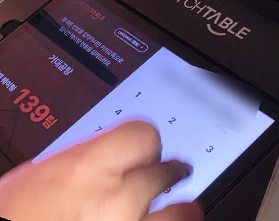 A CatchTable waitlist tablet at a restaurant door in Busan showing 현재 웨이팅 139팀 (139 groups waiting), a LANGUAGE button and a number pad for a Korean mobile number