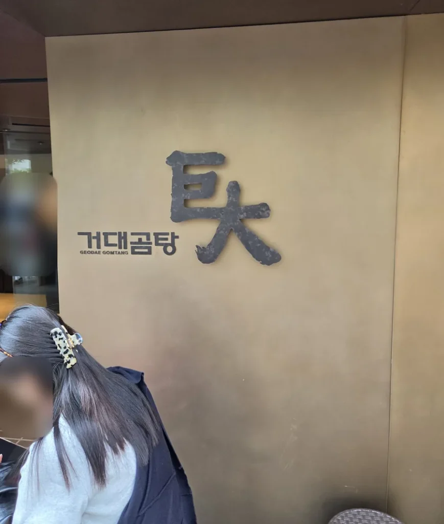 The entrance wall of Geodae Gomtang in Haeundae, with the brushstroke characters 巨大 (geodae, giant) beside the Korean name 거대곰탕