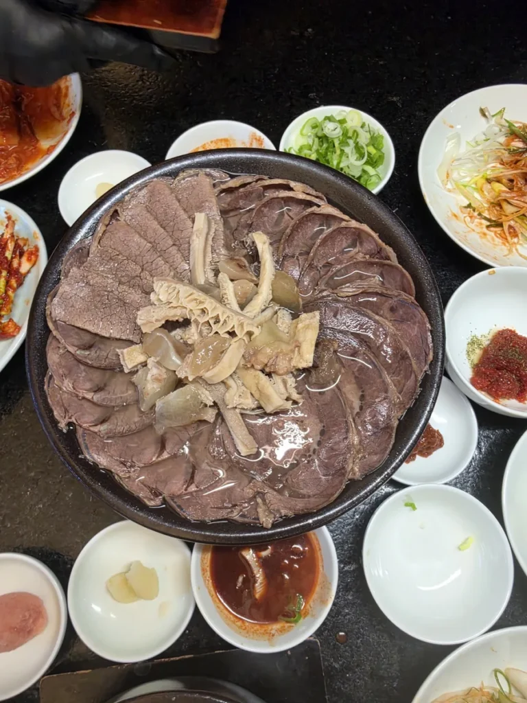 A medium pot of 한우수육 at Geodae Gomtang: thin slices of boiled Korean Hanwoo beef in a ring with tripe in the centre, surrounded by side dishes